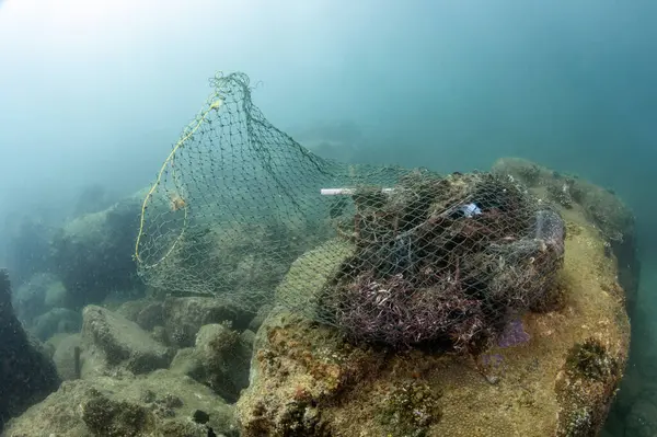 stock image Clean up the ocean by collecting waste. Abandoned debris fishing net or ghost net and plastic garbages in the sea. Save the ocean and underwater world from trash pollution. Environmental conservation