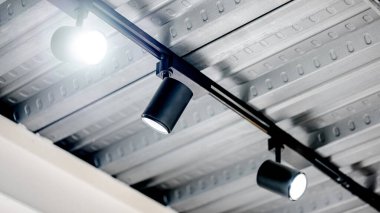 Metalik tavanda asılı modern siyah spot lambası. Müze, galeri ve sergi içi nesneleri için ışıklandırma tasarımı