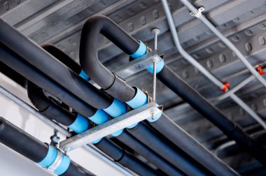 Metal tavanda siyah borular var. Su sistemi için boru hattı bağlantısı