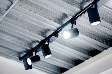 Metalik tavanda asılı modern siyah spot lambası. Müze, galeri ve sergi içi nesneleri için ışıklandırma tasarımı