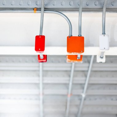 Modern binanın tavanında renkli elektrik kabloları için elektrik bağlantı kutusu olan elektrik kablosu kanalı. Güç sistemleri için boru ve montaj ekipmanları