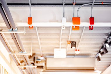 Modern binanın tavanında sergi lambası ve boru hattı olan elektrik kablosu ve bağlantı kutusu. Güç, ışıklandırma ve pompalama sistemleri için boru ve montaj ekipmanları