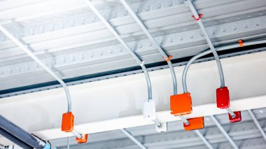 Modern binanın tavanında renkli elektrik kabloları için elektrik bağlantı kutusu olan elektrik kablosu kanalı. Güç sistemleri için boru ve montaj ekipmanları