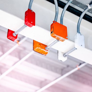 Modern binanın tavanında renkli elektrik kabloları için elektrik bağlantı kutusu olan elektrik kablosu kanalı. Güç sistemleri için boru ve montaj ekipmanları