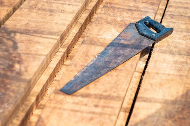 Şantiyedeki kereste yığınının üzerinde eski bir el testeresi. Kereste endüstrisinde kesim için çalışma aracı