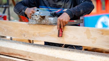 Erkek marangoz, ahşap kareler ve ahşap döşemeler için cetvel kullanır atölyedeki tezgahta elektrikli planör tarafından planlanır. Kereste endüstrisi için odun ölçme ve tıraş süreci