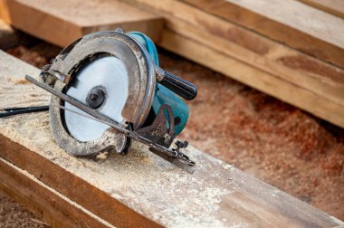 Kereste yığınında elektrikli testere. Ahşap tahta kesmek için kullanılan bir atölyede marangozluk aleti. Kereste endüstrisi konsepti