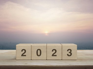 2023 mektup ahşap blok küpleri ahşap masa üzerinde şehir kulesi ve gökdelen üzerinde gün batımında, klasik tarzda, mutlu yıllar 2023 kapak konsepti