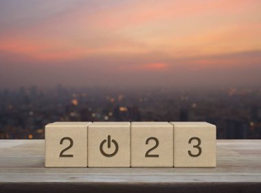 2023 ahşap küpler üzerine ahşap masa üzerine iş ikonu kurun sıcak gün batımında şehir manzarası bulanıklığı, mutlu yıllar 2023 başarı konsepti