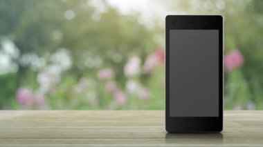 Gift box happy new year 2023 flat icon on modern smart mobile phone screen on wooden table over blur pink flower and tree in garden, Business happy new year 2023 shop online concept