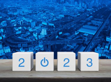 2023 Beyaz Blok küpleri üzerine iş simgesi başlat modern şehir kulesi, sokak, ekspres yol ve gökdelen üzerinde ahşap masa üzerinde. Mutlu yıllar 2023 başarı konsepti.