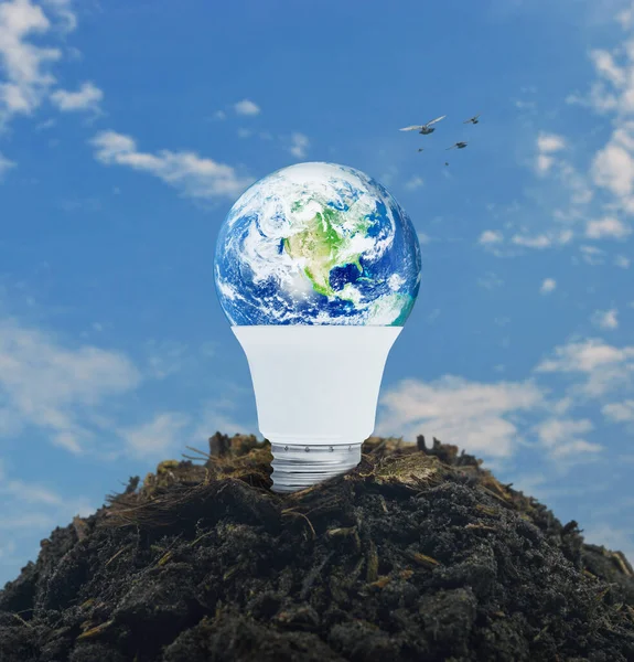 Earth globe inside led light bulb on soil over blue sky with white clouds, Ecology saving power and energy concept, Elements of this image furnished by NASA