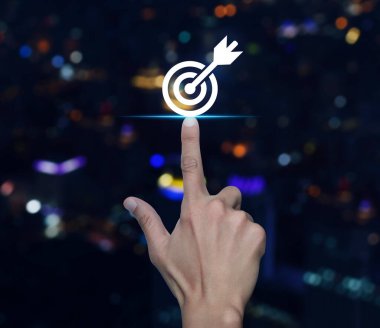 Bulanık renkli gece lambası üzerinde dart ikonuyla el sıkışan hedef modern şehir kulesi ve gökdelen, iş başarısı konsepti