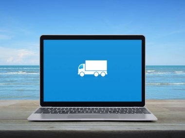 Modern dizüstü bilgisayar ekranında, beyaz bulutlu mavi gökyüzü ve tropikal deniz üzerindeki ahşap masada, iş ulaşımı çevrimiçi servis konsepti