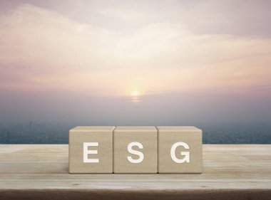 ESG letter on wood block cubes on wooden table over city tower and skyscraper at sunset, vintage style, Environmental Social Corporate Governance concept