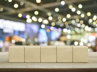 Bulanık ışığın ve alışveriş merkezinin gölgesinin üzerindeki ahşap masanın üzerinde beş tahta blok küp.