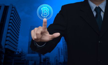 İş adamı, bitcoin simgesini modern ofis kulesi ve gökdelen üzerine bastırıyor, bitcoin konseptini seçiyor