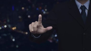 İş adamı, e-öğrenim daire simgesini bulanık renkli gece lambası, modern şehir kulesi ve gökdelen üzerine basıyor.