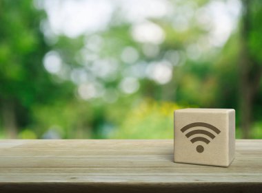 Tahta kübün üzerindeki Wi-fi simgesi parktaki bulanık yeşil ağacın üzerinde, teknoloji internet iletişim konsepti
