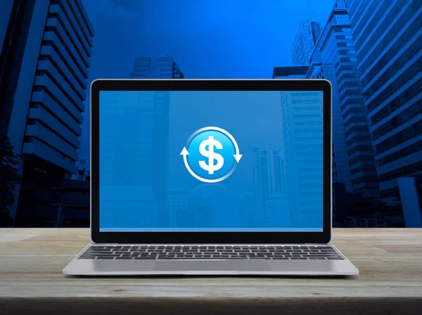 stock image Money transfer icon with modern laptop computer on wooden table over office city tower and skyscraper, Business currency exchange online service concept