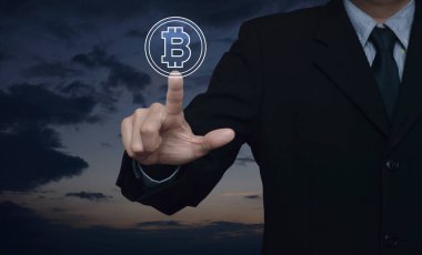 İş adamı bitcoin simgesini gün batımında gökyüzüne bastırıyor, bitcoin konseptini seçiyor