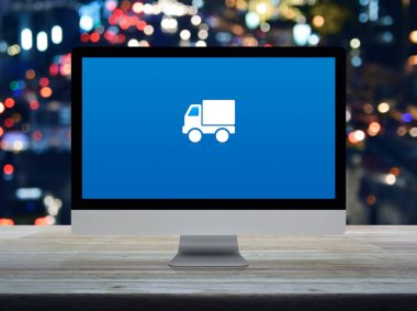Masaüstü modern bilgisayar monitöründeki kargo kamyonu düz simgesi ahşap masa üzerindeki bulanık gece ışığı trafik sıkışıklığı yolu, iş ulaşımı çevrimiçi servis konsepti