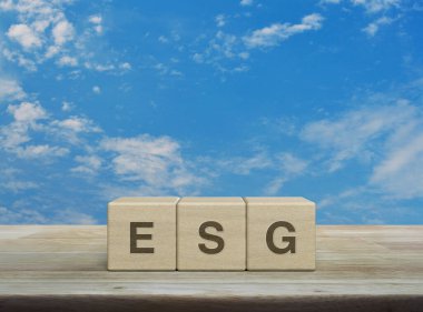 Tahta küpler üzerine ESG harfi beyaz bulutlu mavi gökyüzü üzerine ahşap masa üzerinde, Çevresel Sosyal Yönetim kavramı