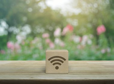 Tahta sehpanın üzerindeki tahta bloktaki Wi-fi simgesi parkta pembe çiçek ve ağaç, teknoloji internet iletişimi konsepti