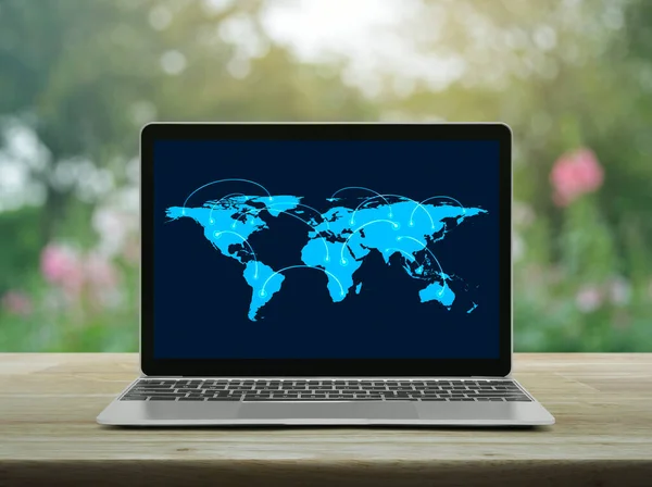 Connection line with global world map on laptop computer screen on wooden table over blur pink flower and tree in garden, Business communication online concept, Elements of this image furnished by NASA