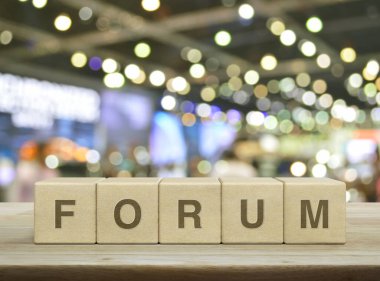 Forum letter on wood block cubes on wooden table over blur light and shadow of shopping mall, Business communication concept clipart