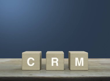 Tahta küpler üzerine CRM harfi açık mavi duvar üzerine ahşap masa, Müşteri İlişkileri Yönetimi kavramı