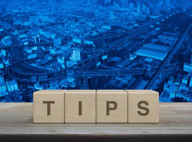 Tahta blok küplere yazılmış TIPS mektubu modern şehir kulesi, sokak, gökdelen, iş dünyası müşteri hizmetleri ve destek kavramının üzerindeki ahşap masa üzerinde.
