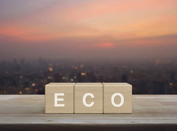 stock image Eco letter on wood block cubes on wooden table over blur of cityscape on warm light sundown, Business ecological concept