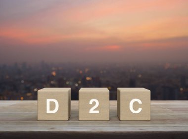 D2C acronym on wood block cubes on wooden table over blur of cityscape on warm light sundown, Direct to Consumer concept