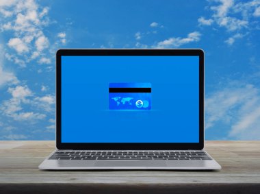 Modern dizüstü bilgisayardaki kredi kartı ekranı mavi gökyüzü üzerindeki ahşap masa üzerinde beyaz bulutlar, online e-ödeme konsepti, NASA tarafından desteklenen bu görüntünün elemanları