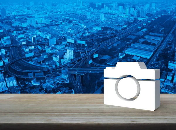 Camera 3d icon on wooden table over modern city tower, street, expressway and skyscraper, Business camera service shop concept