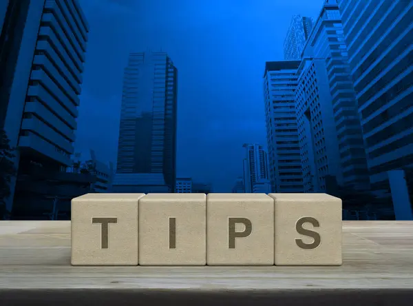 Tahta blok küplere yazılmış TIPS mektubu modern ofis kulesi ve gökdelen üzerinde ahşap masa üzerinde müşteri hizmetleri ve destek konsepti