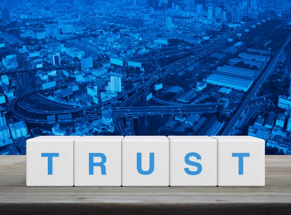 stock image Trust letter on white block cubes on wooden table over modern city tower, street, expressway and skyscraper, Building trust business concept