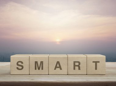 Tahta blok küplerdeki akıllı harf şehir kulesinin üzerindeki ahşap masa ve günbatımında gökdelen, klasik tarz, iş başarısı konsepti.