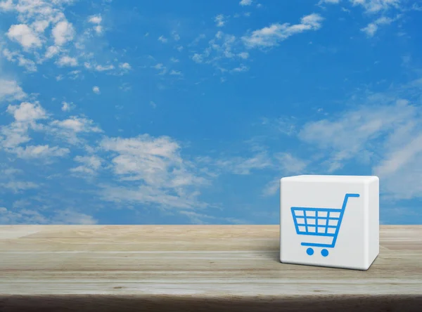 Shop cart icon on white block cube on wooden table over blue sky with white clouds, Business shopping online concept