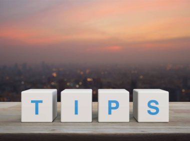 Sıcak gün batımında şehir manzarası bulanıklığı, iş dünyası müşteri hizmetleri ve destek konsepti üzerine beyaz blok küpleri üzerine TIPS mektubu.