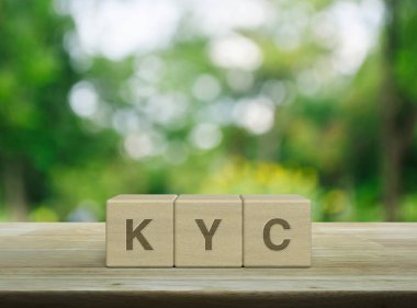 Tahta küpler üzerindeki KYC kısaltması parktaki bulanık yeşil ağacın üzerindeki ahşap masa. Müşteri konseptini biliyorum.