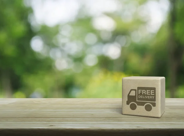 Free delivery truck icon on wood block cube on wooden table over blur green tree in park, Business transportation service concept