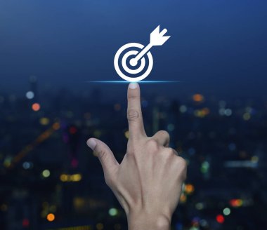 Bulanık renkli gece lambası üzerinde dart ikonuyla el sıkışan hedef modern şehir kulesi ve gökdelen, iş başarısı konsepti