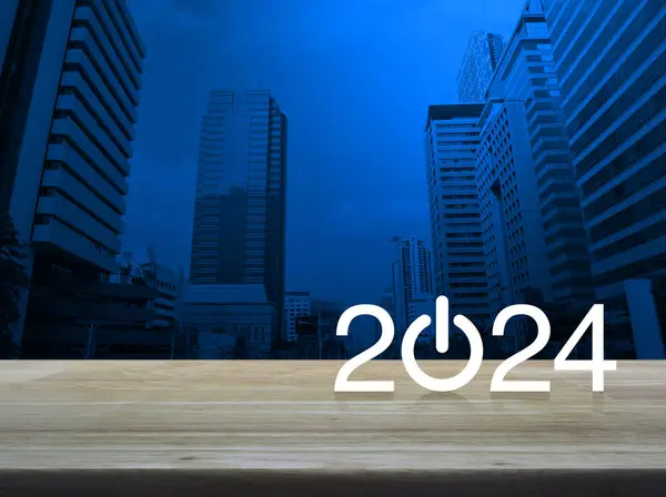 2024, modern ofis kulesi ve gökdelenin üzerindeki ahşap masa üzerinde yeni bir iş simgesi oluşturun. Mutlu yıllar 2024 başarı konsepti.