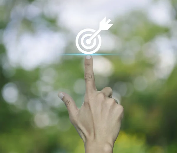 Hand pressing target with dart icon over blur green tree in park, Business success concept