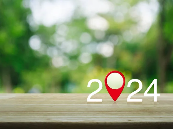 2024 letter with map pin location icon on wooden table over blur green tree in park, Happy new year 2024 map pointer navigation concept