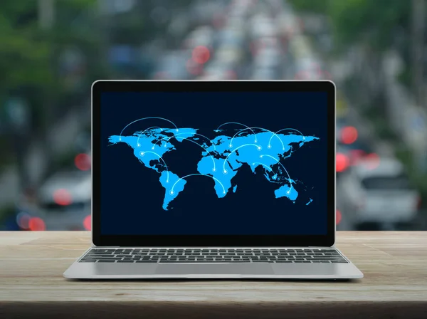 Connection line with global world map on laptop computer monitor screen on wooden table over blur of rush hour with cars and road in city, Business communication online concept, Elements of this image furnished by NASA