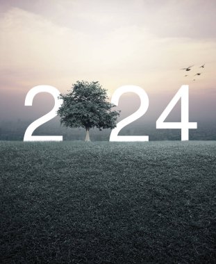 2024 beyaz harf, yeşil çimen tarlasında ağaçla birlikte günbatımında şehir manzarasının havadan görünüşü, klasik tarz, mutlu yeni yıl 2024 ekolojik kavramı.