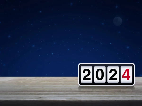 Retro flip clock with 2024 text on wooden table over fantasy night sky and moon, Happy new year 2024 cover concept